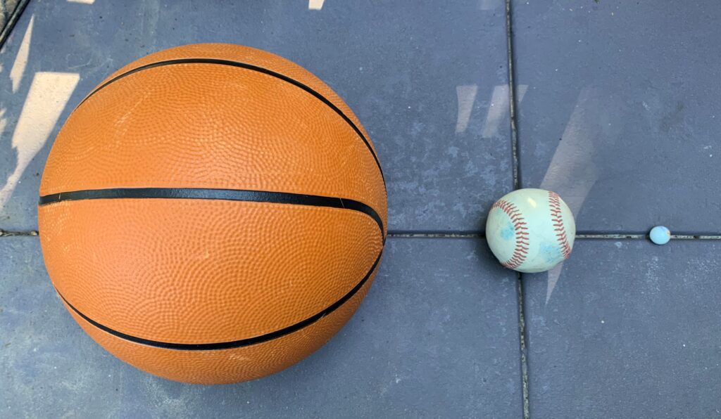 This is an image comparing the sizes of sand, silt, and clay together. The basketball represents sand, the baseball represents silt, and the marble represents clay.