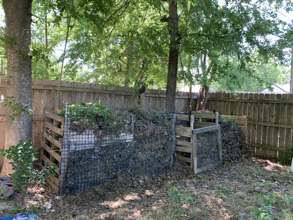 Photo shows a four-bay compost bin. My method is not meant to be beautiful.  It is meant to be cheap, easy, and  not requiring professional carpentry skills.